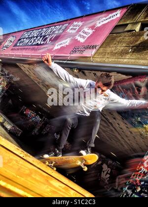 Ein Skateboarder startet in einen Sprung an der Skate-Park in die unter Riss der Southbank Centre, London, England, UK. Stockfoto