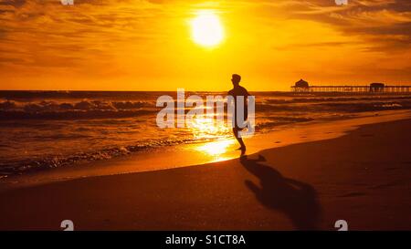 Junger Mann läuft auf eine California Beach bei Sonnenuntergang. Platz für Kopie. Stockfoto