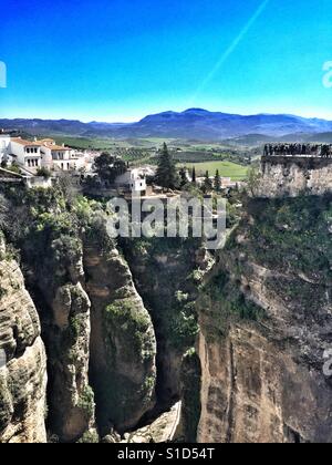 Touristen stehen am Rande der Stadt Ronda, Andalusien, mit Blick auf die Landschaft unter. Von der Puente Nuevo genommen Stockfoto
