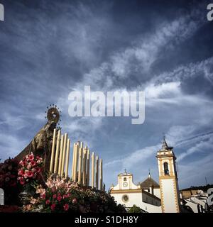 Ein Bild der Jungfrau Maria von Karmel in der Osterwoche unter einem Himmel fallenden Ebene Wanderwege (bekannt als Chemtrails) in Prado del Rey, Sierra de Cadiz, Andalusien, Spanien angezeigt Stockfoto