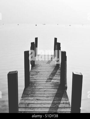 Ein Holzsteg oder Pier erstreckt sich in die Fluten des Lac d ' Annecy, Frankreich. Stockfoto