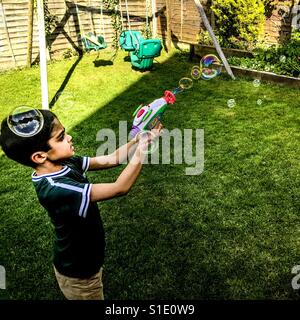 Mit Luftblasen im Garten spielen. Stockfoto