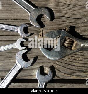 Flexible Schraubenschlüssel gegen eine Vielzahl von Open-End Schraubenschlüssel auf Holztisch Stockfoto
