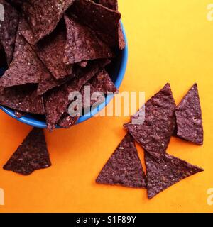 Blaue Tortilla-chips in eine Schüssel geben Stockfoto