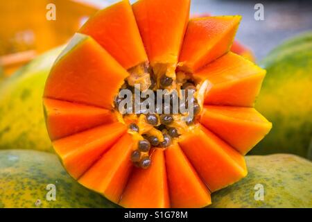 Nahaufnahme von Schneiden kunstvoll orange farbigen Papaya sitting on Top of andere papayas Stockfoto