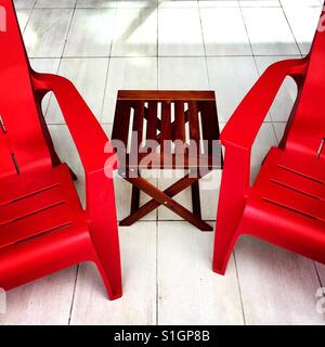 Leere rote Stühle und ein Holztisch auf einer Terrasse im freien Stockfoto