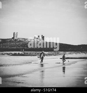 Surfer am Strand in der Nähe von Dunstanburgh Castle. Stockfoto