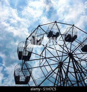 Silhouette von einem Riesenrad vor einem blauen bewölkten Himmel. Stockfoto