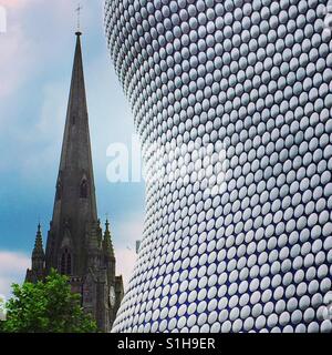 Das moderne Design der Selfridges Gebäude in Birmingham, UK kontrastiert gegen den Turm einer benachbarten Kirche Stockfoto