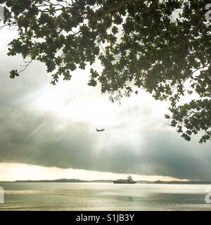 Himmel und Meer, Schiff und Flugzeug. Ein Treffen von Elementen zwischen Maschine und Natur, eingefangen in Singapur Changi Village beach Stockfoto