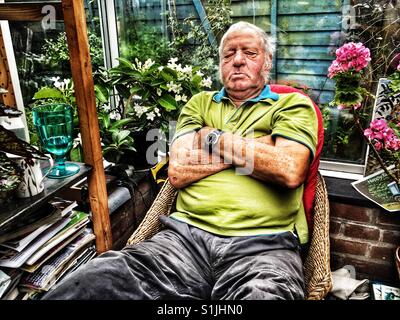 Älterer Mann schlief während der Sitzung in einem Wintergarten in seinem Haus Suffolk Stockfoto