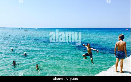 Griechischen Jungen springen ins Ägäische Meer in Chalkidiki, Griechenland. Stockfoto