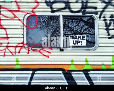 Fenster von einem Graffiti bedeckt Wohnmobil mit Schild Wake Up Stockfoto