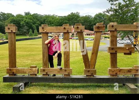 Verliebt in Luray, Virginia, salutieren, weibliches Modell. Modell in großen hölzernen Buchstaben O in einer Liebe-Anzeige auf Picknickplätze am Luray Caverns, salutieren Virginia. Stockfoto