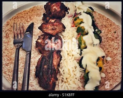 Feurige Jamaican Jerk Chicken mit Tortilla, Reis, saure Sahne und Mango Salsa. Stockfoto