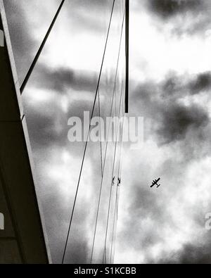Vintage Flugzeug im bewölkten Himmel spiegelt sich in einem modernen Gebäude Stockfoto