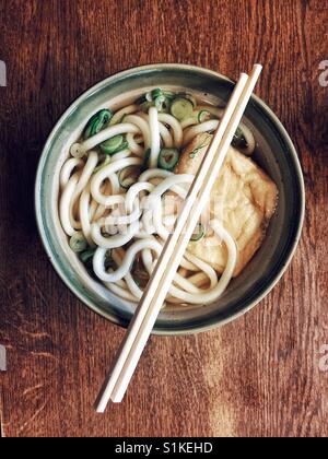 Klassische japanische Ramen-Suppe in Steinzeug Schale und Bambus Stäbchen oben auf rustikalen Holztisch Stockfoto