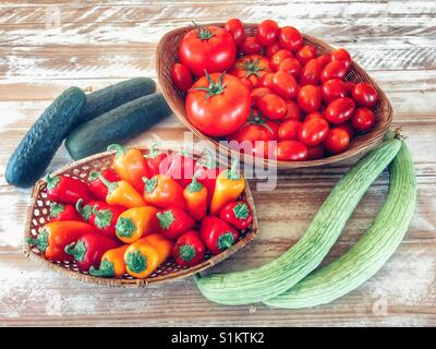 Obst und Gemüse: Gurken, armenische Gurken, Tomaten, verschiedene kleine Paprika in einem Korb Stockfoto