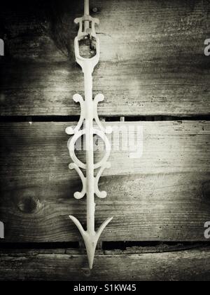 Weißes Gusseisen Wetterfahne Pfeil hängt nach unten in alten Holzschuppen Stockfoto