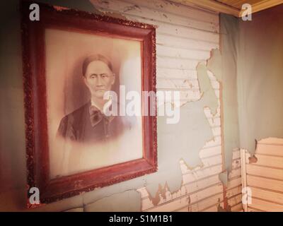 Altes Foto des stern Frau in hölzernen Rahmen, hängen an der Wand mit Peeling grüne Tapeten und weiße Perle board Stockfoto