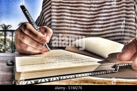 Frau schreiben Liste der Promotion soll in einer Zeitschrift mit einem Stift, der sagt, es Träumen, glauben Sie es, es erreichen. Stockfoto