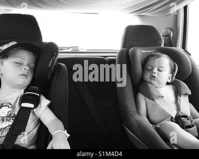 Vorschüler und Baby schlafend in einem Auto. Stockfoto