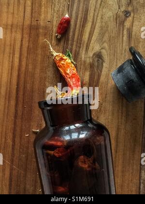 Getrocknete Chilis in einer Flasche auf einem Schneidebrett. Stockfoto