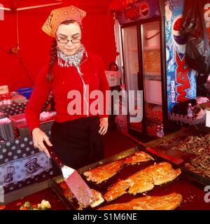 Junge Frau Lachs grillen im freien Markt in Oulu, Finnland Stockfoto