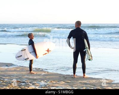 Vater und Sohn Surfer am Strand den Wellen. Pismo Beach, Kalifornien, USA Stockfoto