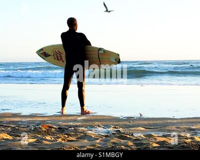 Erwachsene männliche Surfer stehen am Strand mit Blick auf den Ozean. Kalifornien, USA Stockfoto