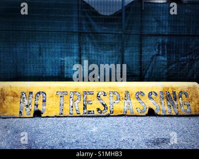 Die Worte "No trespassing" gemalt auf einem gelben Barriere auf einer Baustelle, Nordamerika. Stockfoto