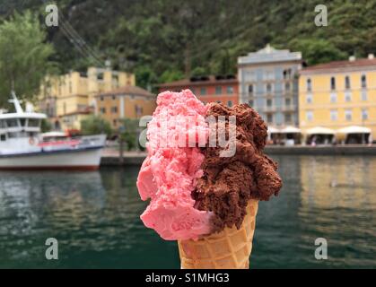 Italienisches Eis "Gelato" mit dem Hafen von Riva del Garda im Hintergrund Stockfoto