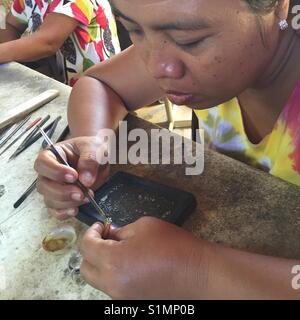 Weibliche Juwelier bei Workbench sitzen konzentriert sich als Sie feine Detail trägt zu klingeln. In der Nähe der weiblichen Silberschmied. Ubud, Bali, Indonesien Stockfoto