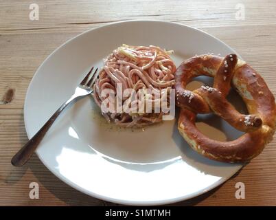 Schweizer Wurstsalat und Bayerische Brezel auf weiße Platte Stockfoto