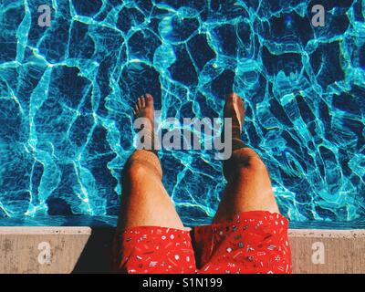 Areal Blick auf die Beine der Menschen, die in den blauen Gewässern des einen Swimmingpool auf einer sonnigen heißen Tag. Stockfoto