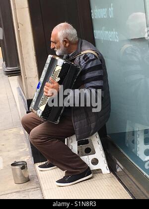 Mann spielt Klavier Akkordeon außerhalb M&S Kensington London Stockfoto