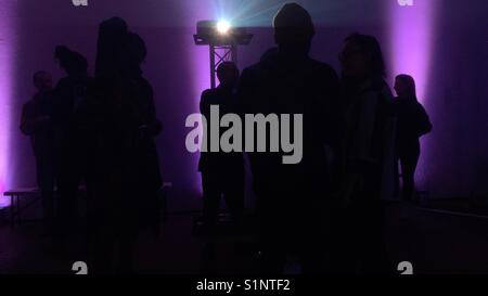 Silhouette von Menschen gegen buntes Licht in einem Veranstaltungsort Teil von Peckham Rye Festival in South East London. Stockfoto
