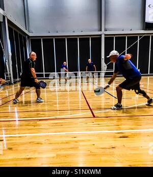 Doppel in Pickleball, ein Spiel in der Halle, Ontario, Kanada. Konzepte: Freundlicher Wettbewerb, Teamwork, Zusammenarbeit, Sport, sportlich, Rentner. Pickle Ball. Männer im Spiel. Bros Stockfoto