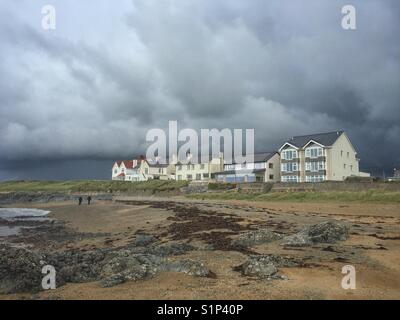 Spaziergänger auf Lion Rock Beach, Rhosneigr, Anglesey, Nordwales Stockfoto