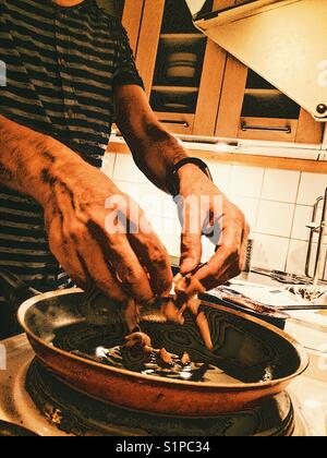 Mann, der zu Hause Sardellen in der Pfanne kocht Stockfoto