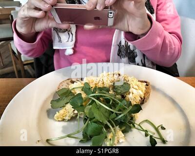 Frau ein Foto von ihr Frühstück auf einem iPhone Stockfoto