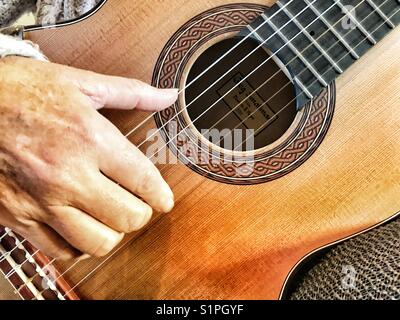 Frau spielen Smallman Gitarre, Nahaufnahme der rechten Hand auf Streicher und Schallloch. Stockfoto