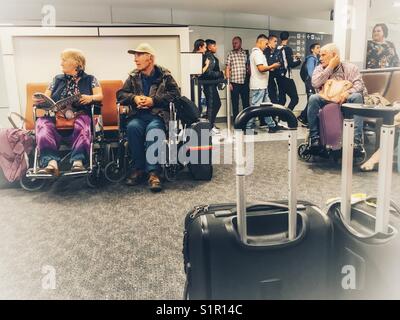 Menschen im Rollstuhl in der geförderten Passagiere der Flughafen Bristol mit einer Gruppe von Studenten zu Fuß Vergangenheit hinter sich. Stockfoto