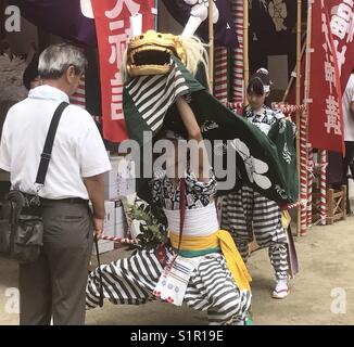 Mensch, der durch die Shishi, Löwe gesegnet, während der Lion Dance an Tenmangu Shinto Schrein während Tenjin Matsuri Festival in Osaka, Japan. Stockfoto