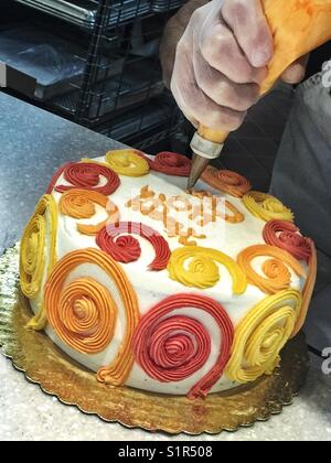 Ein Mann schreibt auf eine bunte Torte mit Puderzucker Stockfoto