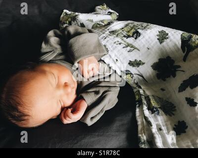Ein schlafendes Neugeborenes, das durch natürliches Licht beleuchtet wird. Stockfoto