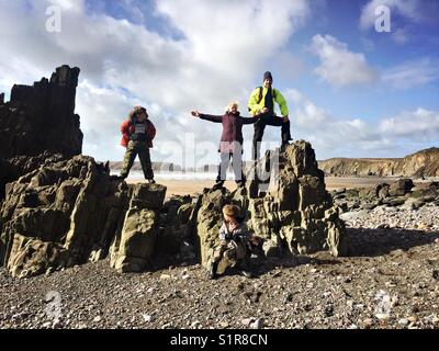 Eine Familie für ein Foto posieren beim Stehen auf Felsen t Marloes Sands Beach in Wales. Stockfoto