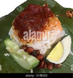 Malaysia Signatur Frühstück; Reis mit Kokosmilch gekocht, würzige Soße auf der Oberseite, Ei, Gurke und Erdnüsse auf einem Bananenblatt Stockfoto