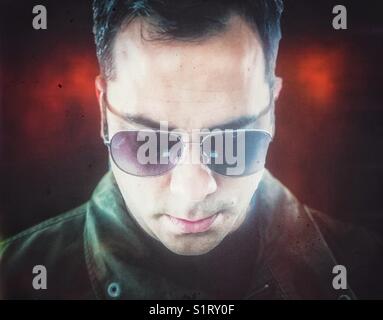 Dunkelhaariger Mann mit Fliegersonnenbrille und Blick auf das Smartphone Stockfoto