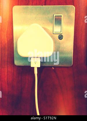 Ein USB-Kabel, das an ein Ladegerät angeschlossen ist, das an eine Steckdose angeschlossen ist. Stockfoto